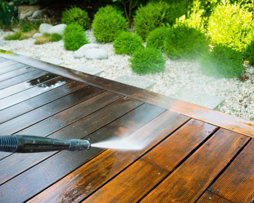 cleaning terrace with a power washer - high water pressure cleaner on wooden terrace surface